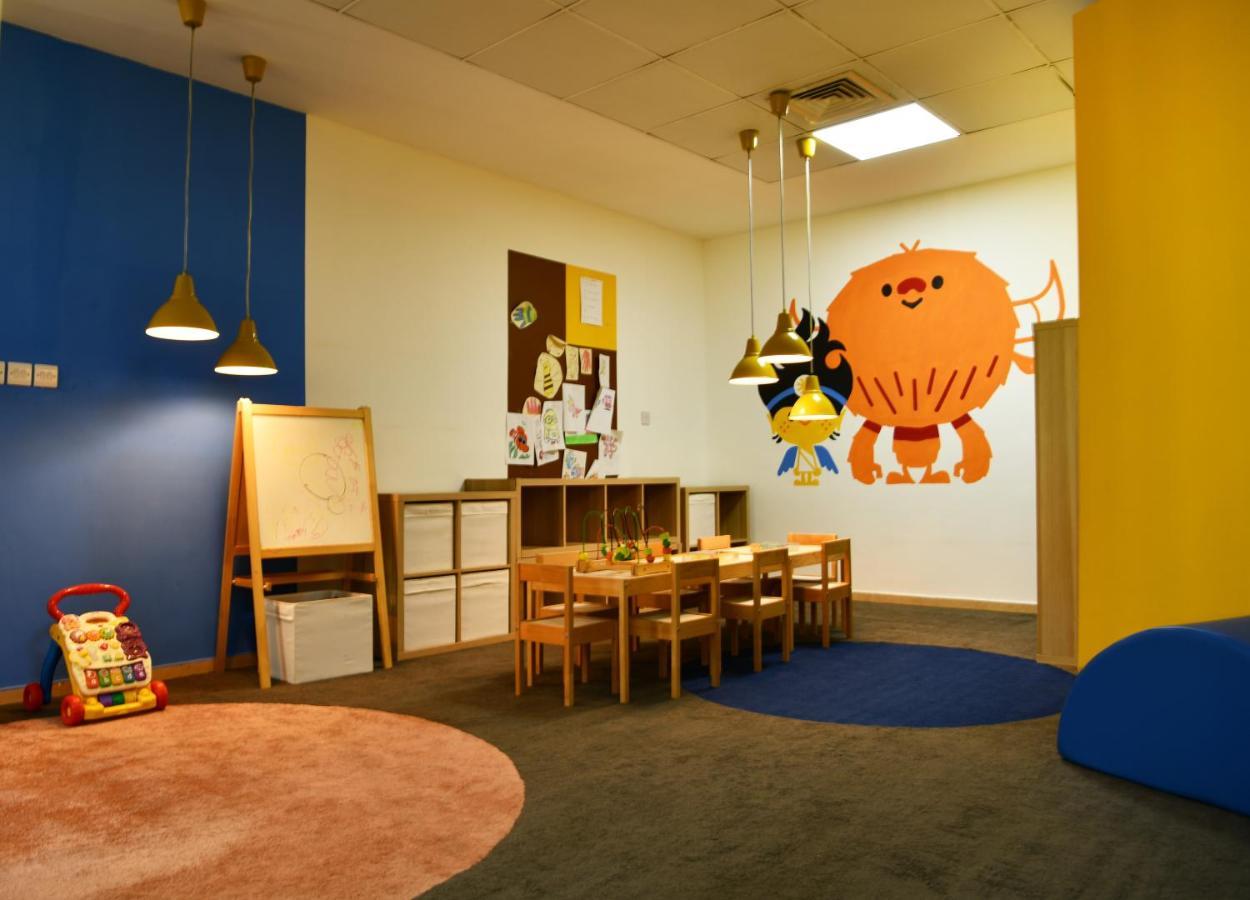Al Raha Beach Resort & Spa Abu Dhabi Exterior foto The photo shows a colorful children's classroom or play area. The walls are painted in various shades, including blue and yellow. There is a large, playful character mural on one wall that appears to be a friendly monster. 

In the room, there is a s