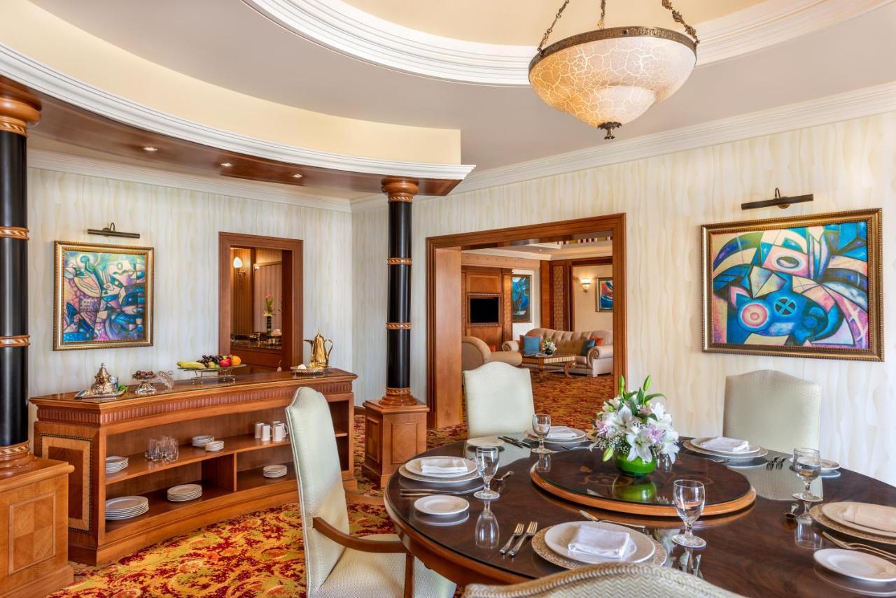 Al Raha Beach Resort & Spa Abu Dhabi Exterior foto The photo shows an elegantly designed dining area and a glimpse into a luxurious living space. 

In the foreground, a round dining table is set with fine china, glassware, and a centerpiece featuring fresh flowers. The chairs surrounding the table ha