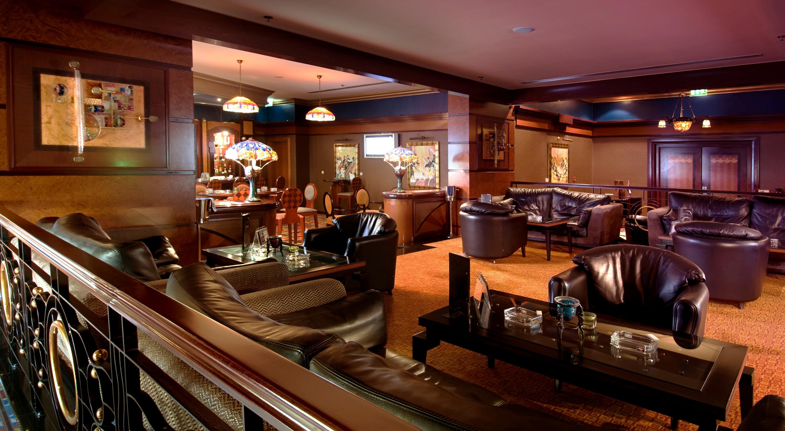Al Raha Beach Resort & Spa Abu Dhabi Interior foto The photo depicts a stylish lounge area featuring comfortable seating and an inviting atmosphere. There are several plush leather armchairs and sofas arranged around low tables. The space is well-lit, with stained glass lamps providing warm light. Th