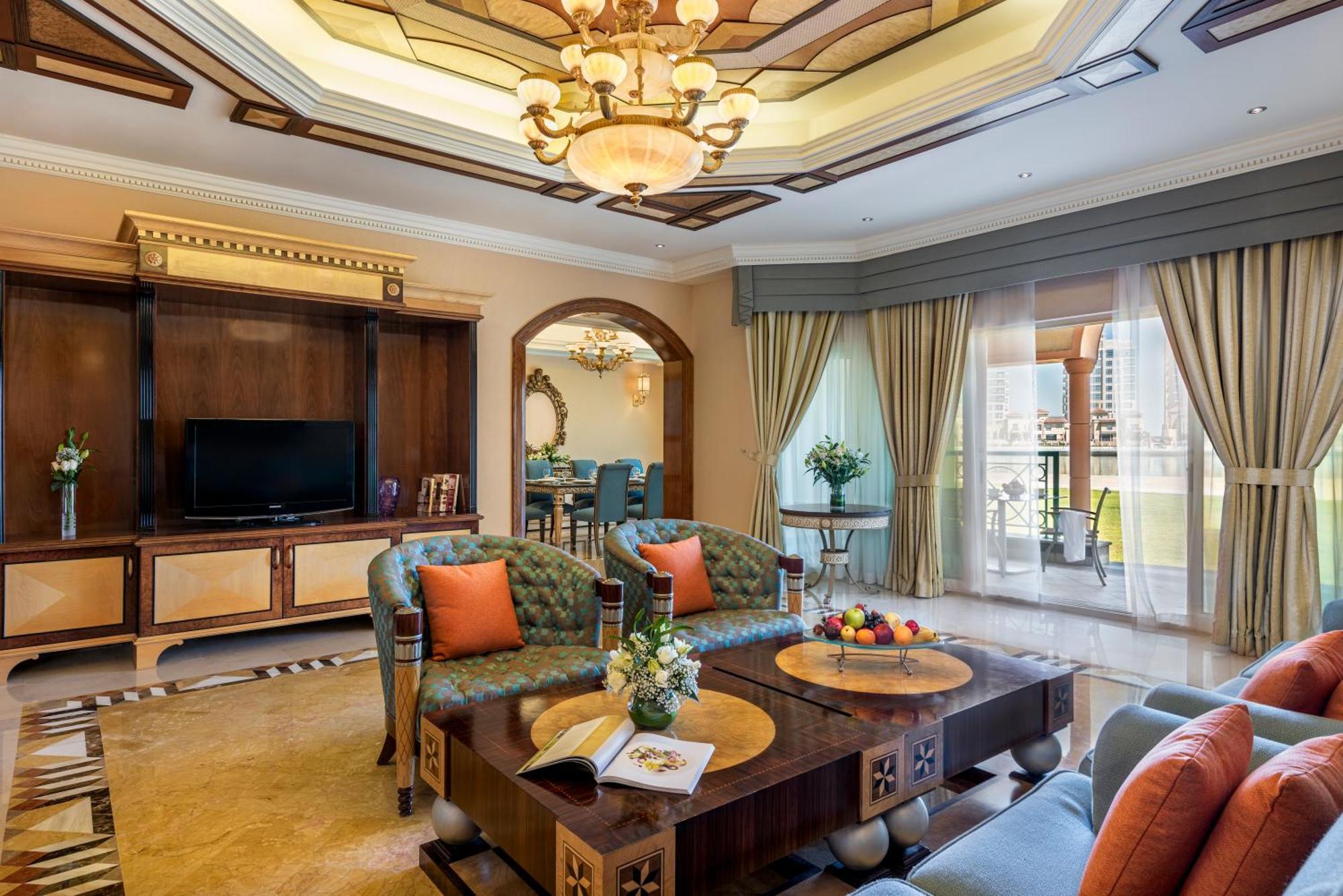 Al Raha Beach Resort & Spa Abu Dhabi Exterior foto The photo depicts a luxurious living room with elegant decor. It features two green upholstered sofas accented with orange pillows, arranged around a stylish coffee table. The coffee table showcases decorative items, including a magazine and a bowl o