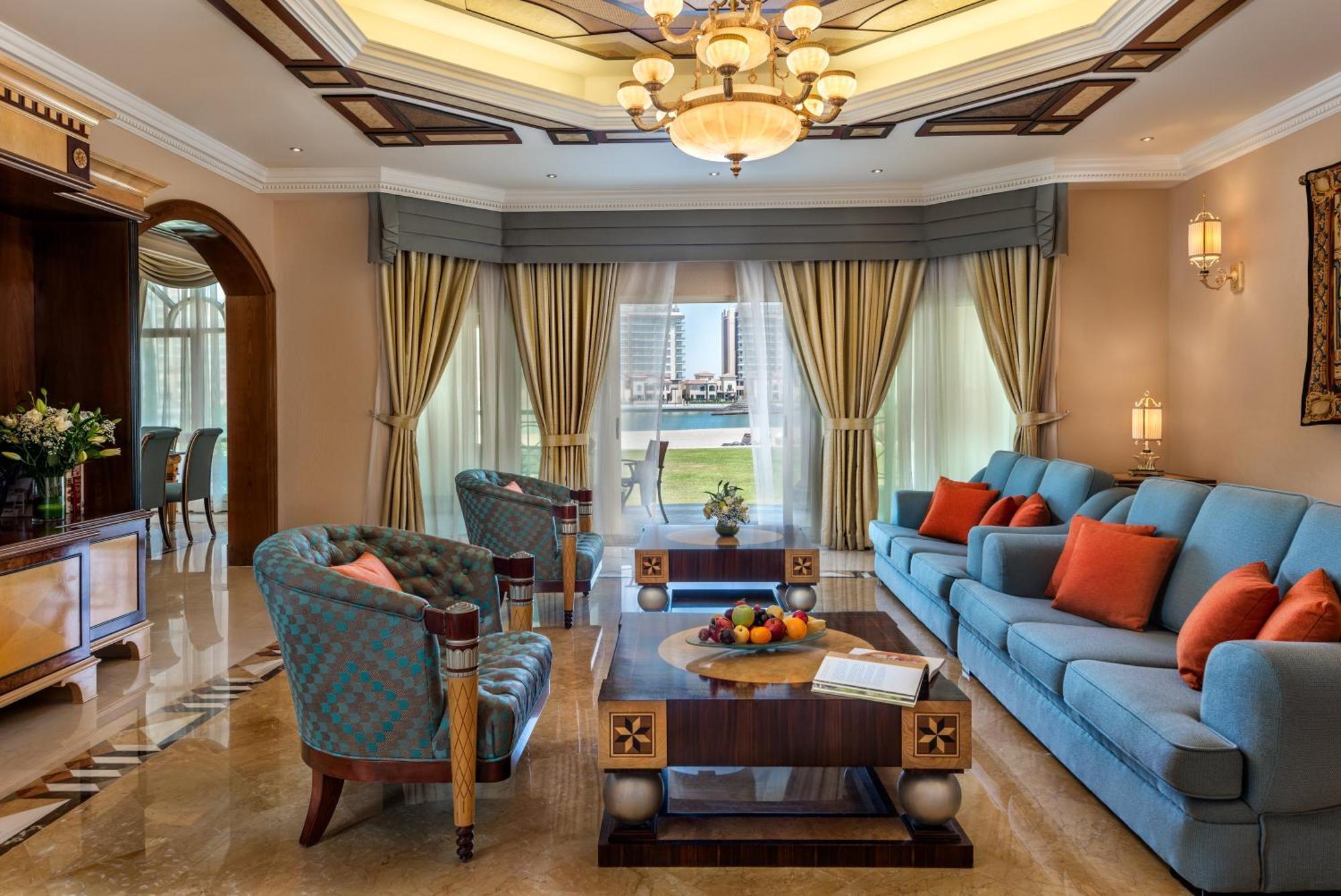 Al Raha Beach Resort & Spa Abu Dhabi Exterior foto The photo depicts an elegantly designed living room with a sophisticated atmosphere. It features a large, light blue sofa adorned with orange and blue cushions. There are two stylish armchairs nearby with a unique pattern. In the center, a coffee tab
