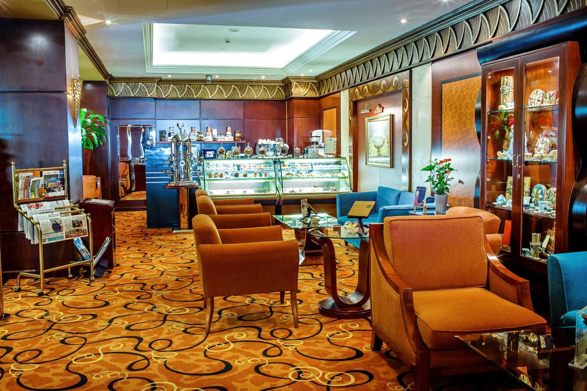 Al Raha Beach Resort & Spa Abu Dhabi Exterior foto The photo shows a cozy and elegantly designed lounge or café area. It features plush seating with brown armchairs and a blue couch. In the background, there is a display case filled with various items, likely including pastries or decorative goods. T